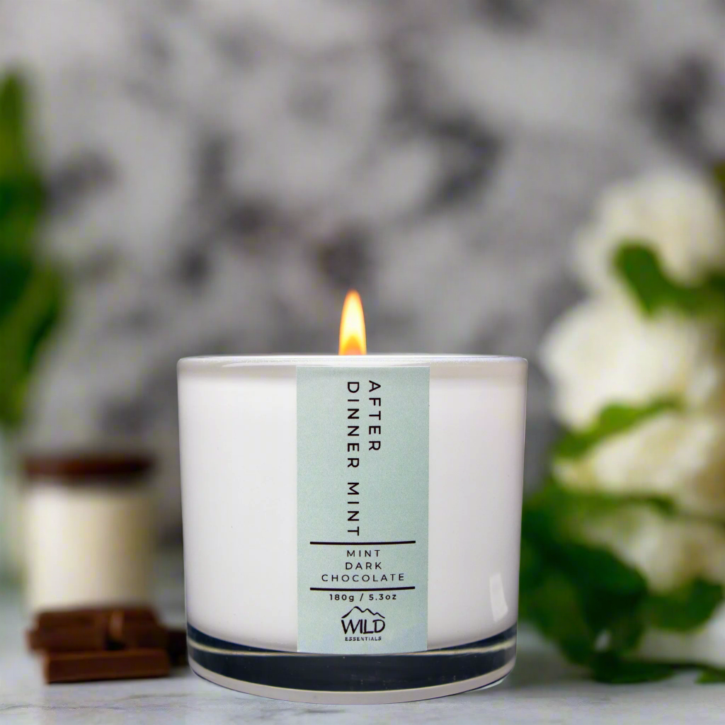 Photo of the After Dinner Mint Candle from Wild Essentials. In the background is some chocolate and what looks like mint. The candle is scented with Mint and Dark Chocolate, hence the name, After Dinner Mint.