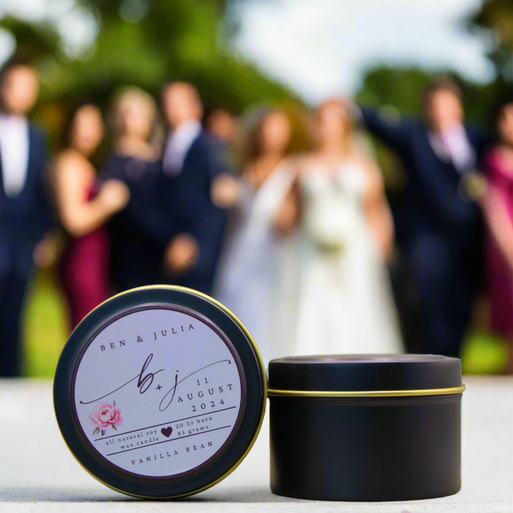 A photo of a Black Candle Tin with a customised logo, taken at a wedding. It is an example of what the Wild Essentials Custom Wedding Candles could look like when produced a for a Client.