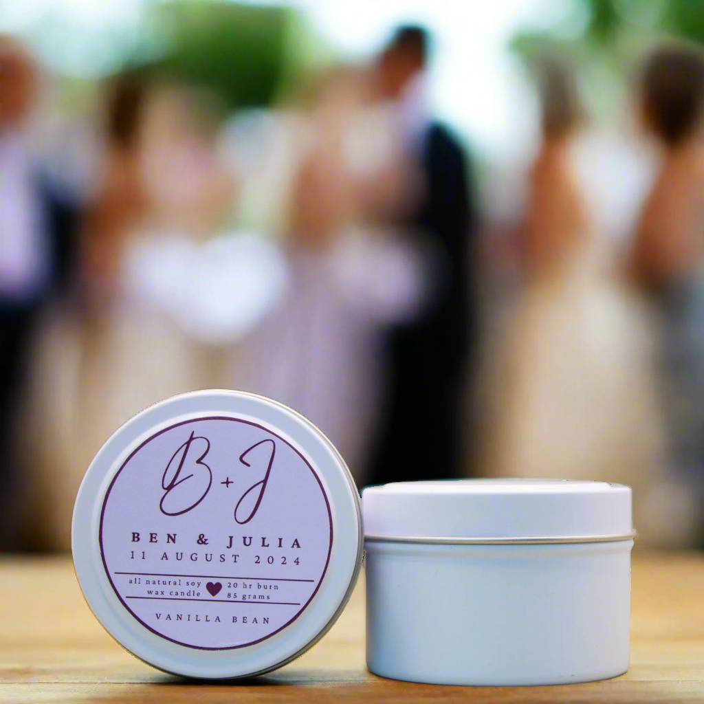 A photo of a White Candle Tin with a customised logo, taken at a wedding. It is an example of what the Wild Essentials Custom Wedding Candles could look like when produced a for a Client.