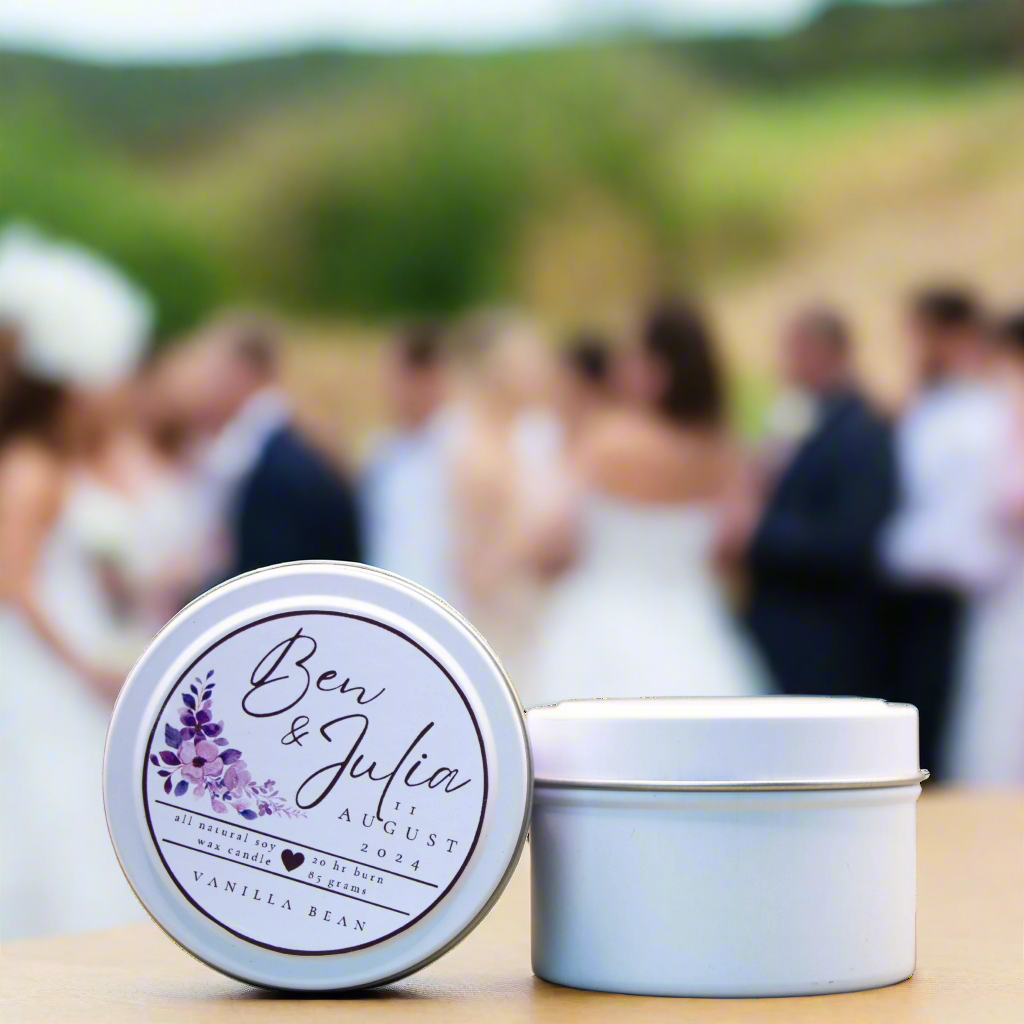 A photo of a White Candle Tin with a customised logo, taken at a wedding. It is an example of what the Wild Essentials Custom Wedding Candles could look like when produced a for a Client.