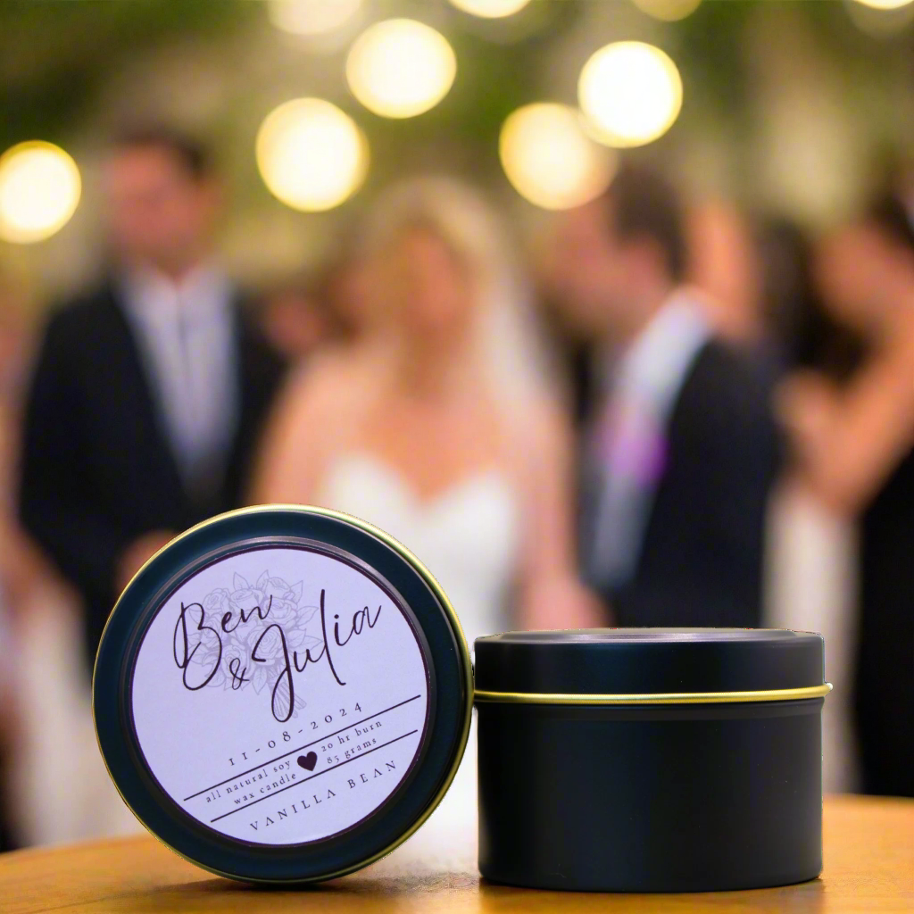 A photo of a Black Candle Tin with a customised logo, taken at a wedding. It is an example of what the Wild Essentials Custom Wedding Candles could look like when produced a for a Client.