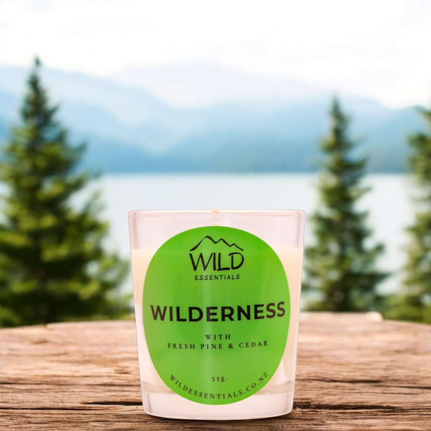Photograph of the Wilderness Mini Candle from Wild Essentials, taken outdoors overlooking a lake and some mountains.