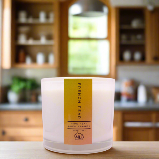 Photo of the French Pear Luxury Candle handcrafted by Wild Essentials. Photo taken in a modern kitchen with wooden cabinetry.