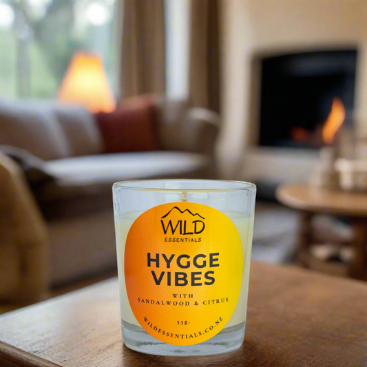 Photo of the Hygge Vibes Mini Candle from Wild Essentials. Photo taken in a cosy lounge with a fire going in the background.