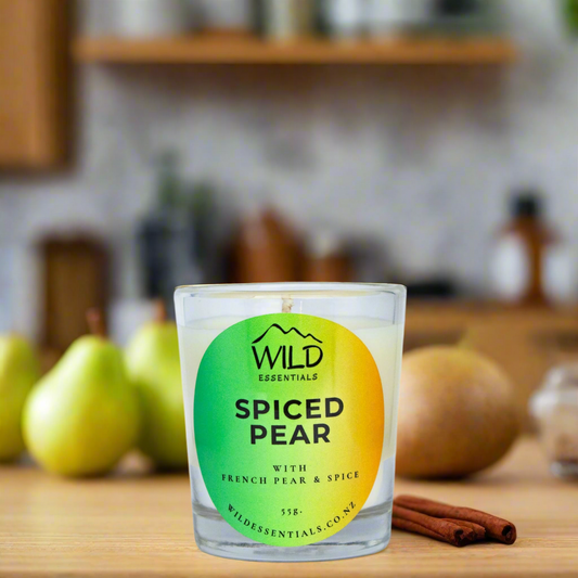 Photo of the Spiced Pear Mini Candle made by Wild Essentials. The photo is taken in a kitchen with pears and cinnamon nearby.